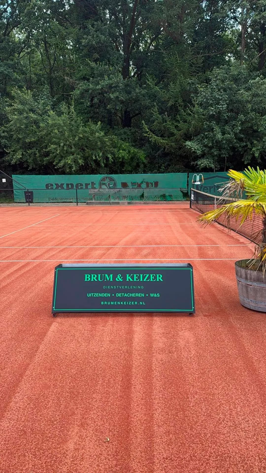 Het sponsorbord van Brum & Keizer langs de gravelbaan van Tennis Club 't Weusthag in Hengelo